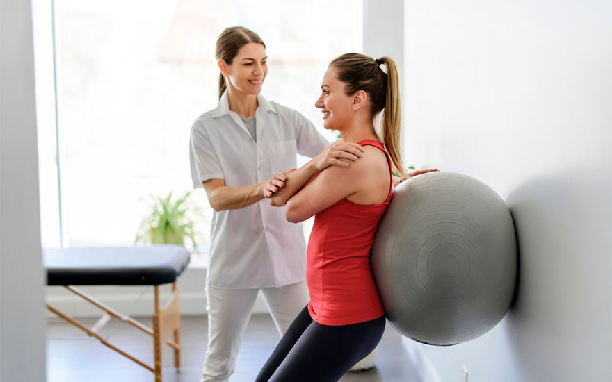 Woman helping patient to do physical therapy